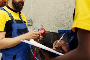 Proficient experts coworkers commissioned to do air conditioner check, refilling freon. Licensed servicemen using barometer set to meticulously measure the pressure in condenser